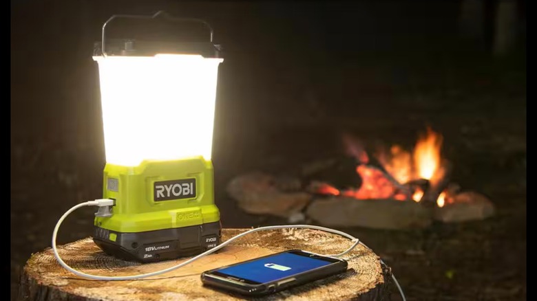 Ryobi's LED Area Light charging a phone at a campsite
