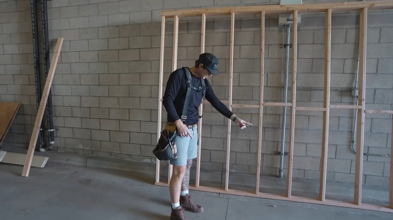 A Construction Worker Demonstrating How To Frame A Wall With Fire Block In-between The Studs