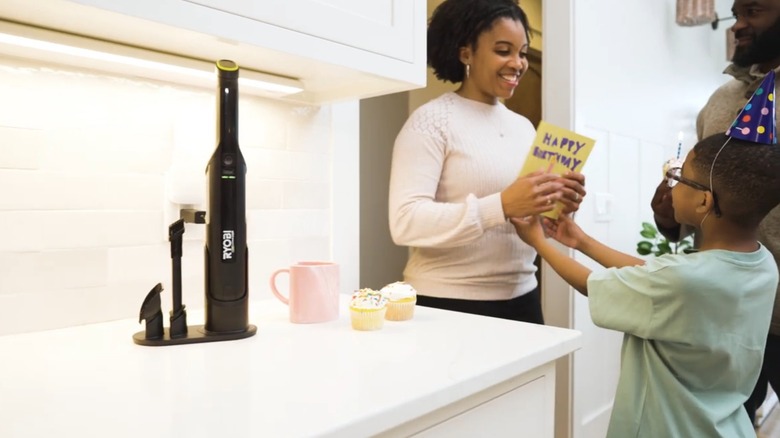 the ryobi handheld vacuum docked on a kitchen counter next to a family celebrating a birthday