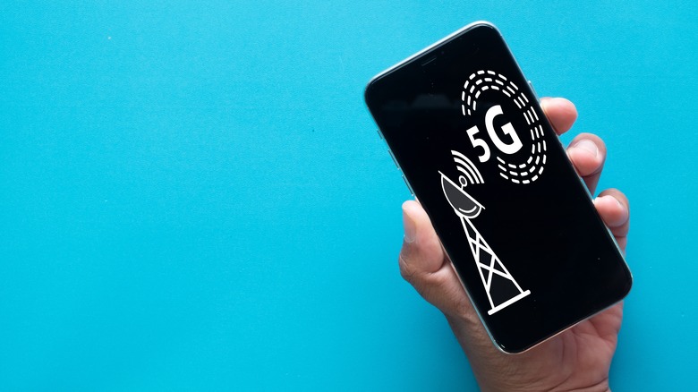 Hand holding phone showing 5G graphics