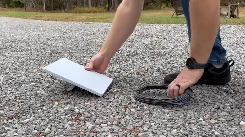 A person placing the Starlink Mini on the ground during setup