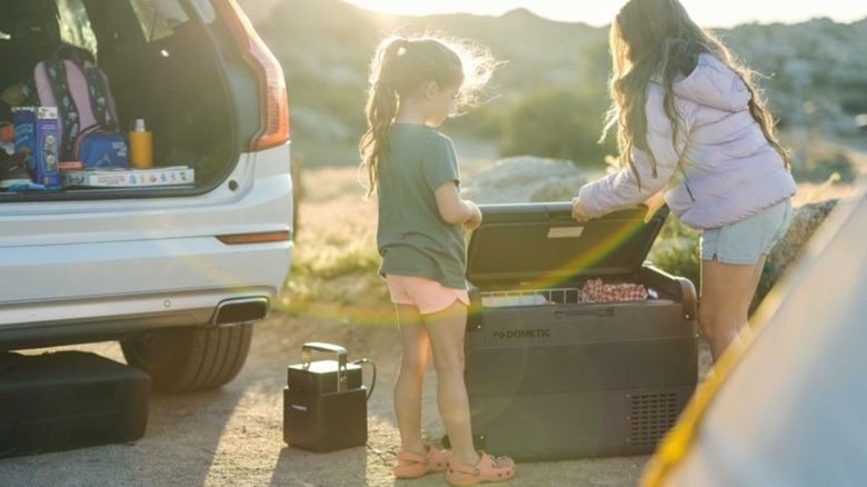 Children opening a Dometic CFX2 electric cooler at a campsite