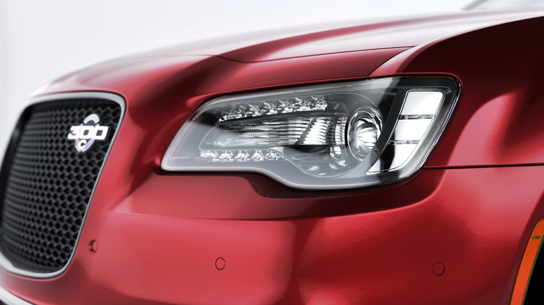 Close-up of a red 2023 Chrysler 300's headlight and grille