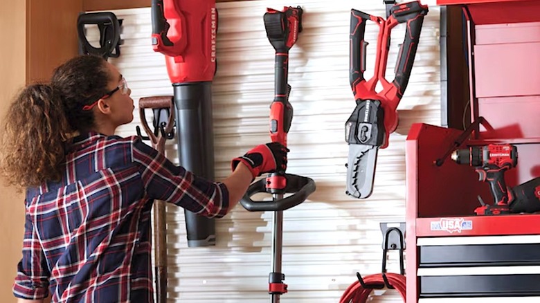 Woman hanging Craftsman tool on a wall