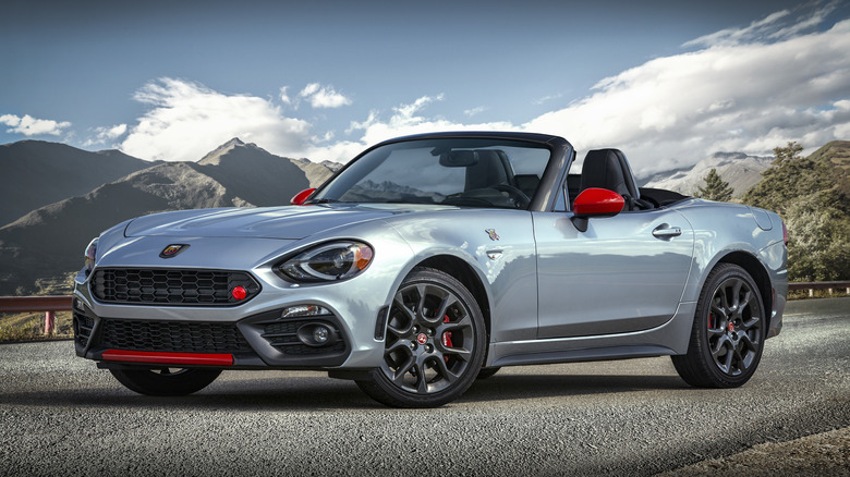 Front left view of a silver Fiat 124 Spider Abarth parked on mountain road with top down