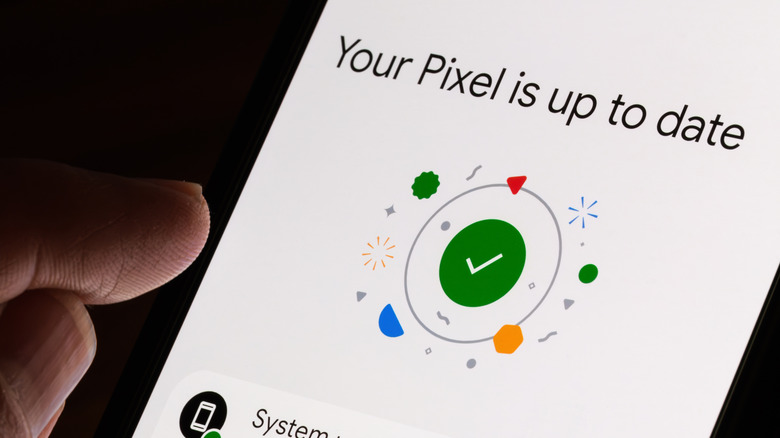 Smartphone display showing Pixel is up to date with a finger about to press on a display