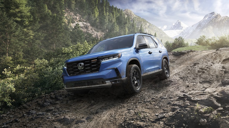 2025 Honda Pilot TrailSport in blue on a muddy trail, front 3/4 view, CG render