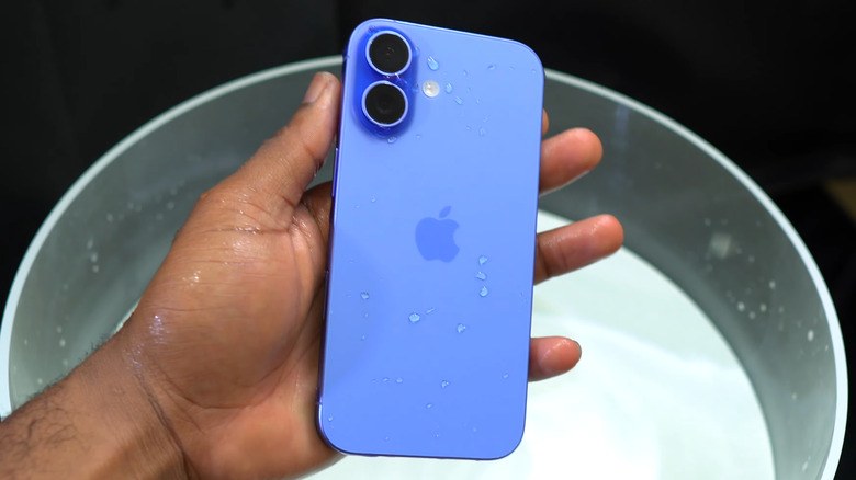 Hand holding iPhone 16 with water droplets on it