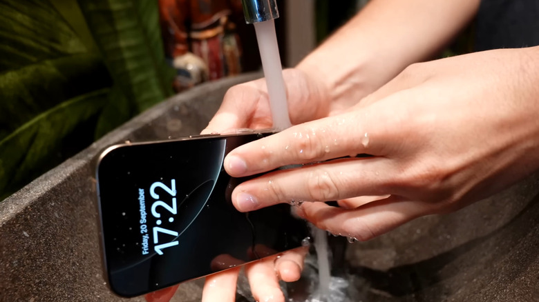 Hands holding iPhone under tap water