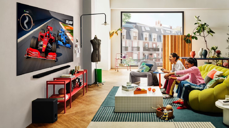 A bright living room with two people sitting on a sofa and gaming on an LG C5