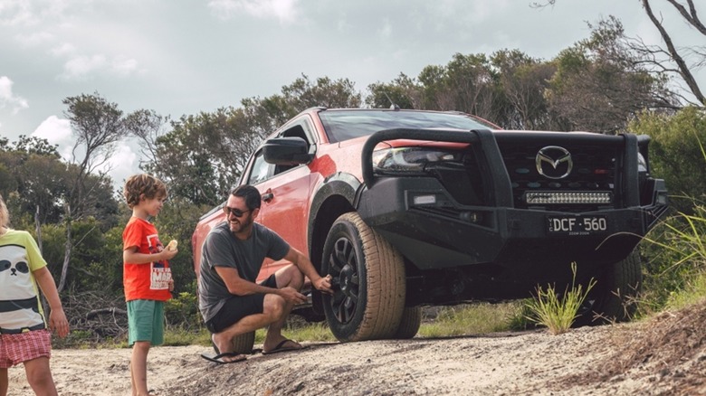 Man and two children next of an orange Mazda BT-50 Ute at the beach