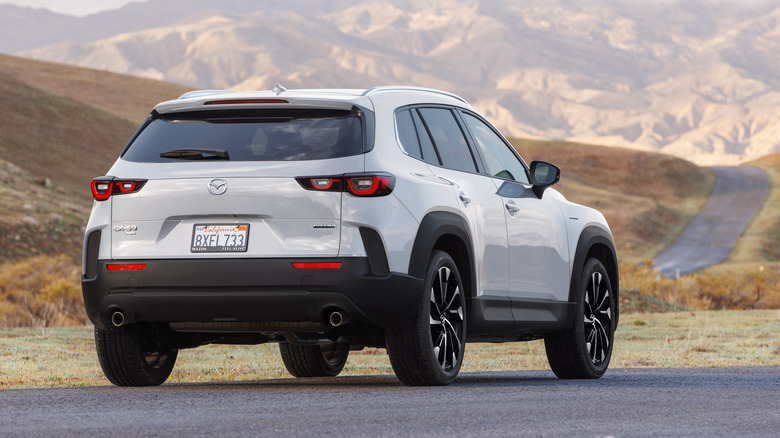 Rear 3/4 view of a white Mazda CX-50 parked on a rural road