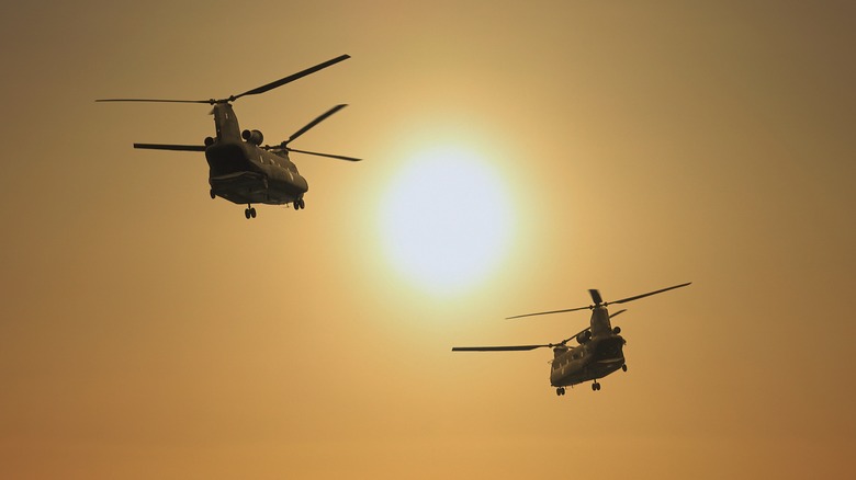 Two CH47 Chinook helicopters mid-flight at sunset