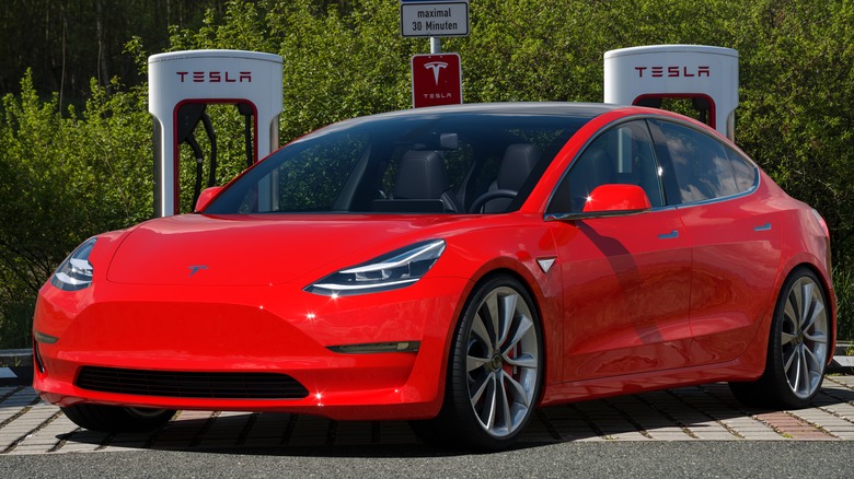 A red Tesla Model 3 at a charging station.