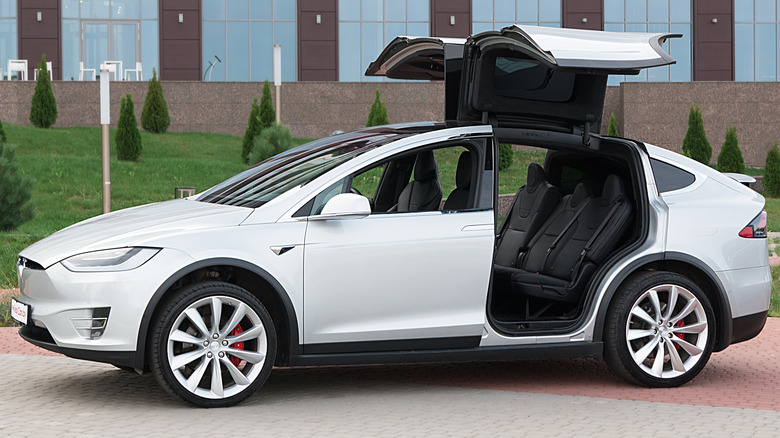 A silver Model X with its doors raised.