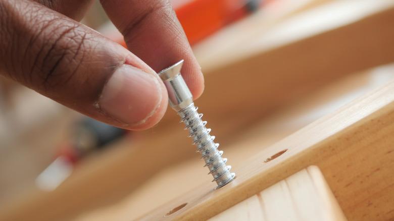 Person placing a screw in place for tightening