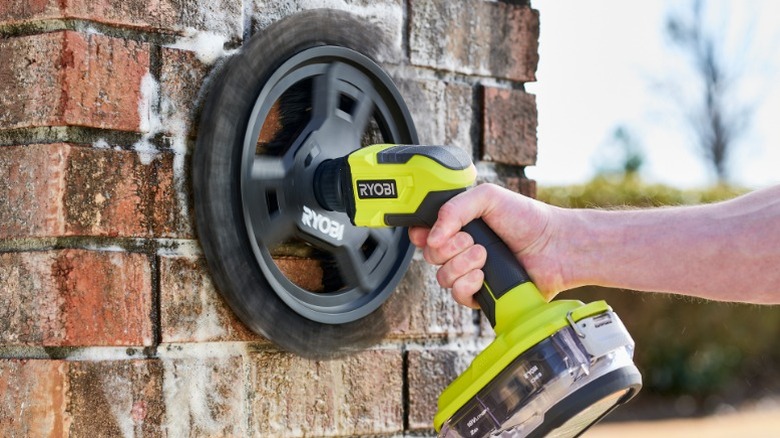 Person using Ryobi Power Scrubber on brick