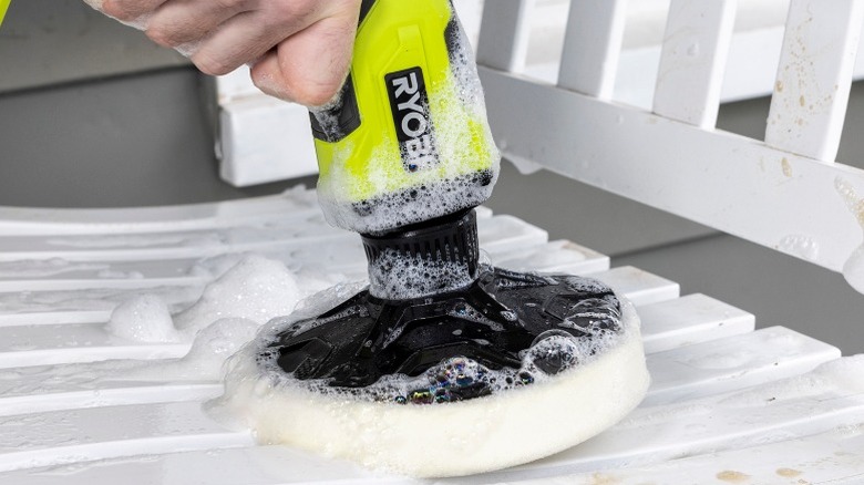 Person cleaning outdoor bench with Ryobi Power Scrubber
