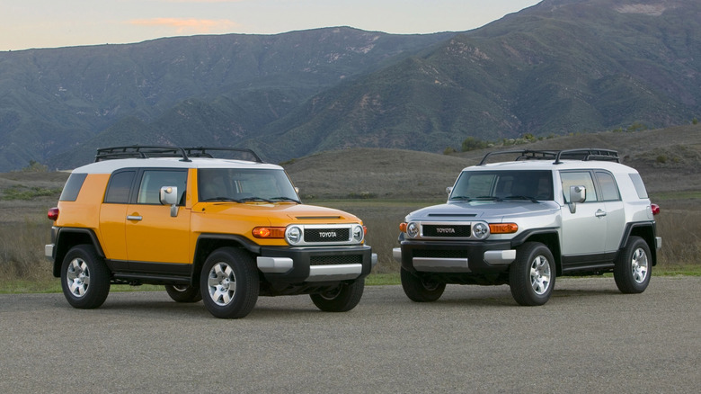 Yellow and silver Toyota FJ Cruisers parked in front of mountains