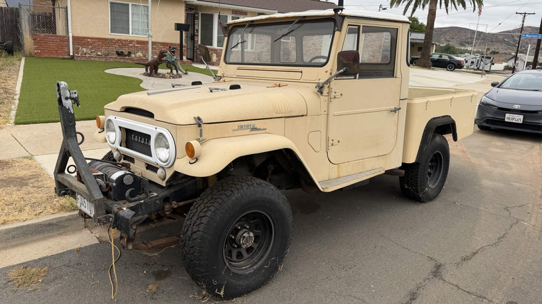 Lightly modified FJ45 Toyota Land Cruiser pickup variant parked on street, front-left 3/4 view.