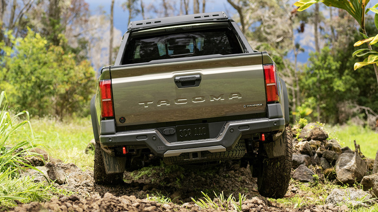 Rear view of green Toyota Tacoma Trailhunter on forest trail.