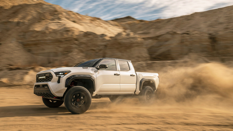 A white Toyota Tacoma TRD Pro with a cloud of dust behind it on an off-road trail