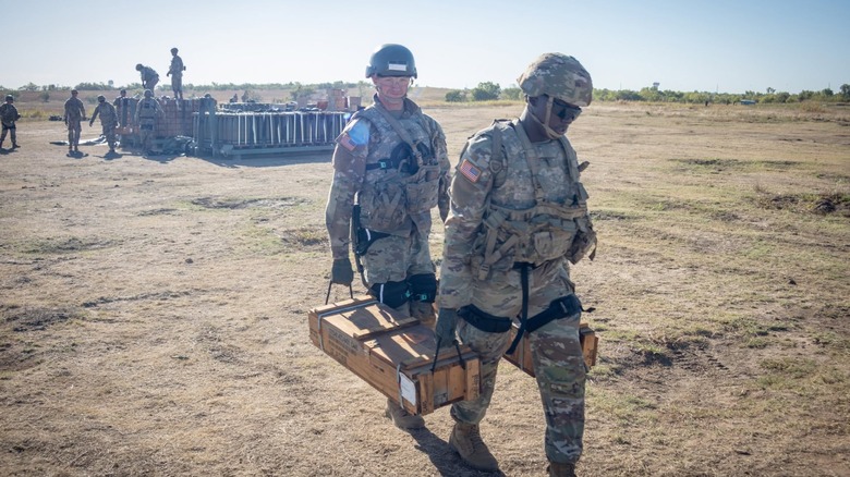 Soldiers carrying heavy equipment while wearing powered exoskeletons