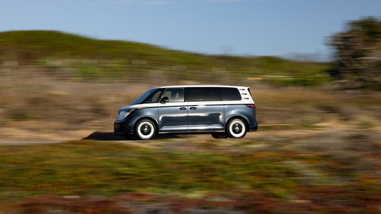 A Volkswagen ID. Buzz in white over dark blue on the move, side view