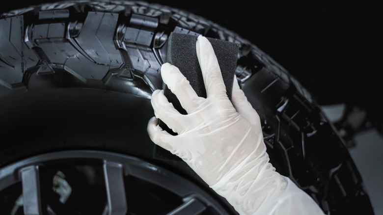 Person using tire shine to spruce up a large tire