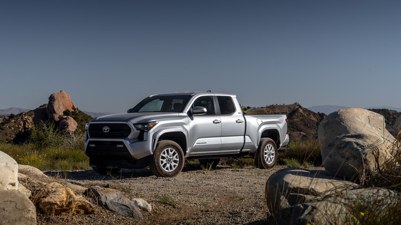 The 2025 Toyota Tacoma in silver next to some rocks, front 3/4 view