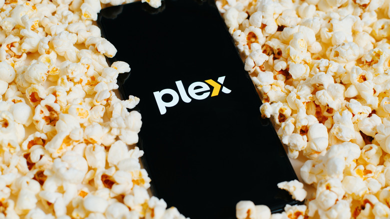 Smartphone lying on popcorn showing Plex logo on screen
