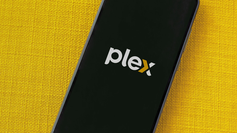 Plex app launch screen on smartphone on yellow fabric background