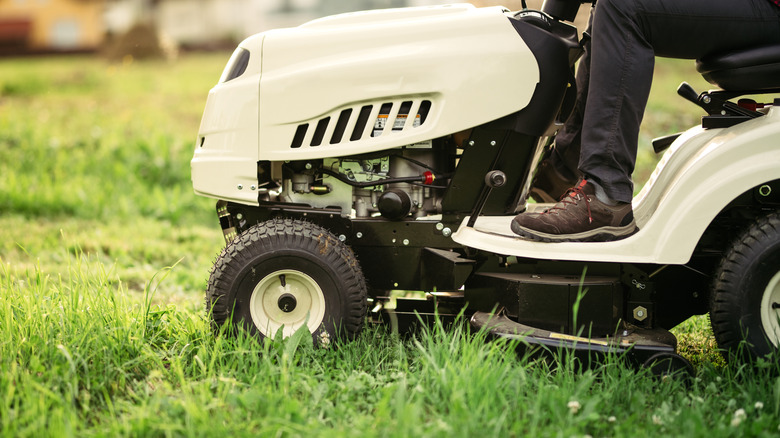 Side view of a person on a white riding mower