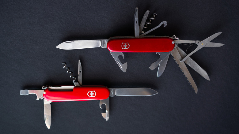 Two swiss army knives on black surface