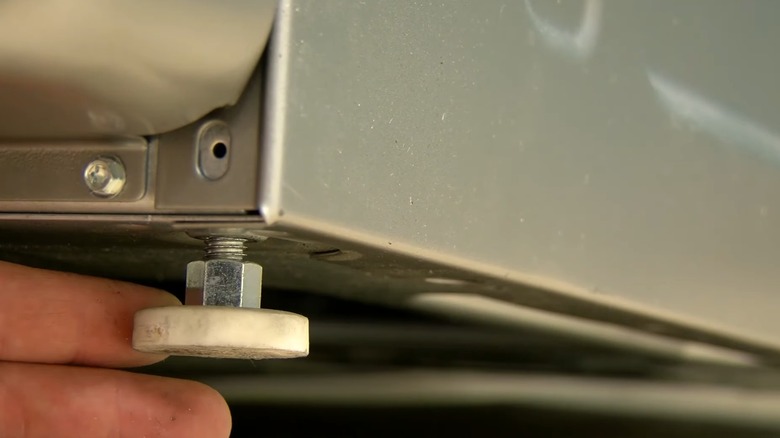 A closeup of person adjusting a a washing machine foot.