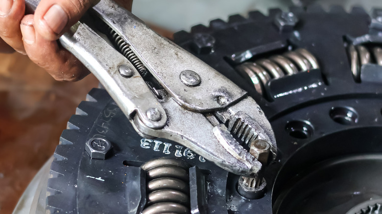 Close-up of a mechanic using a pair of locking pliers to turn a bolt on a transmission