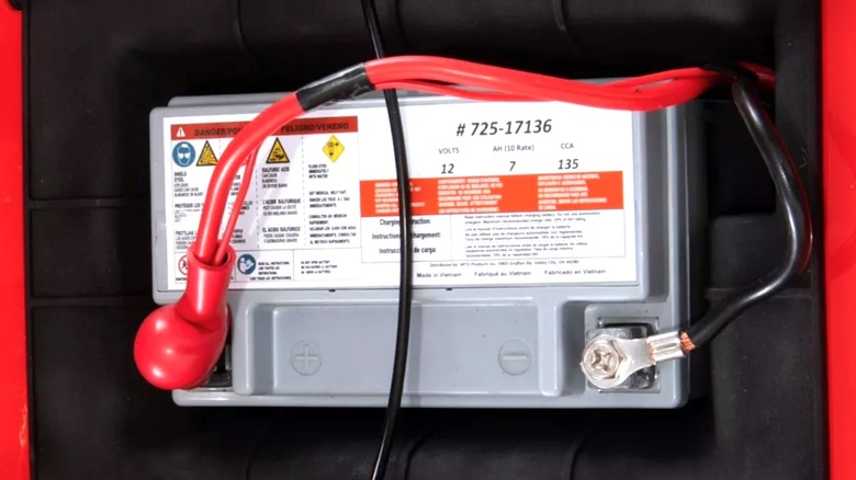 A battery hooked up to the back of a lawn mower
