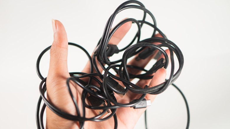 Left hand holding a tangled black USB cable
