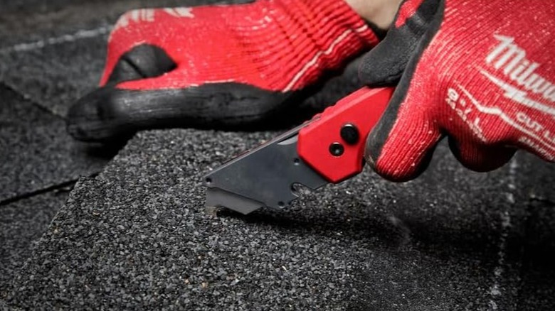 Person using a Milwaukee Utility Knife on a roofing shingle