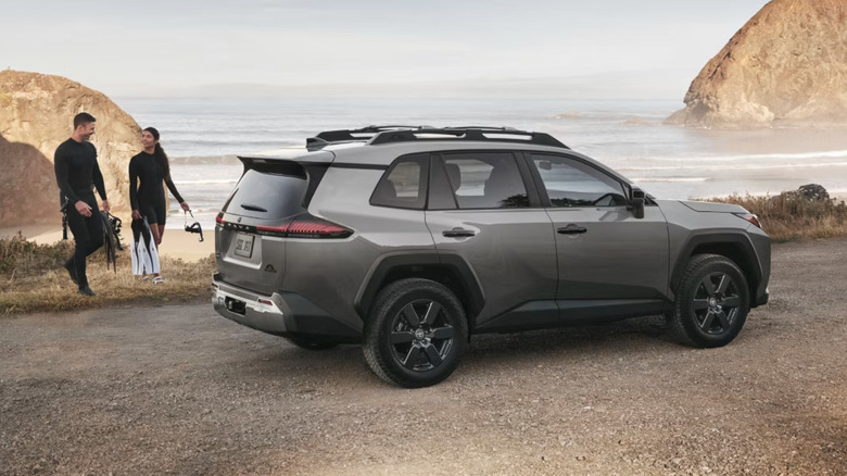 Surfing couple walks toward grey Toyota RAV4 parked near beach