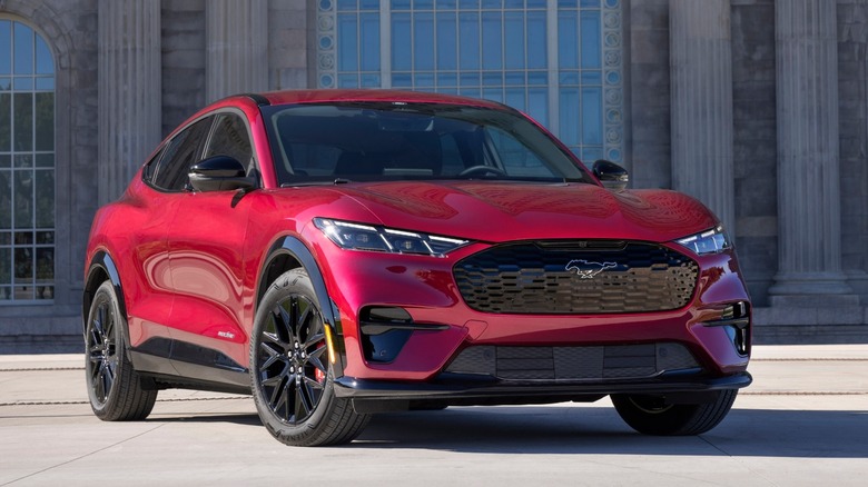 A red Ford Mustang Mach-E parked in front of a building