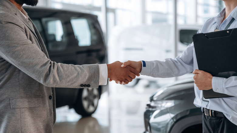 A salesperson and a customer shaking hands at a dealership