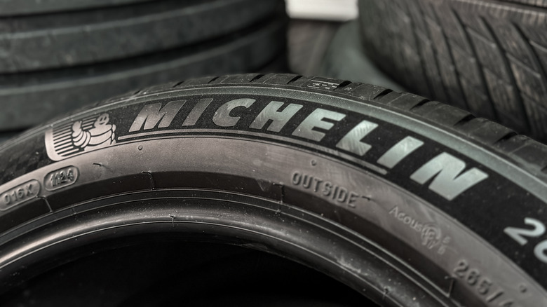 Close-up of a Michelin tire leaning on stacks of tires.
