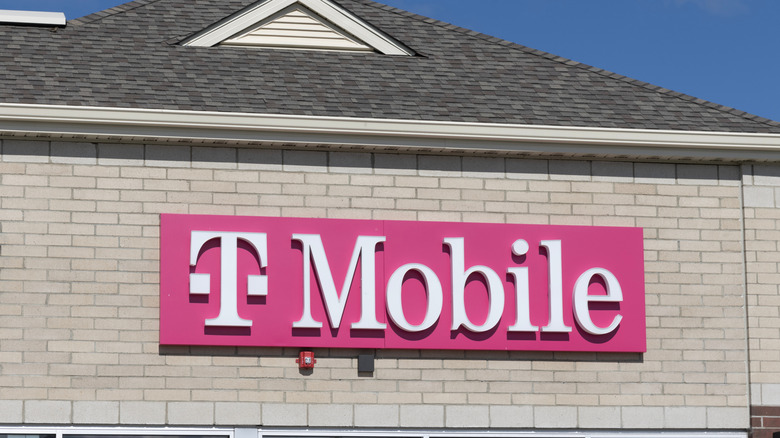 A white brick building with a large pink and white T-Mobile sign