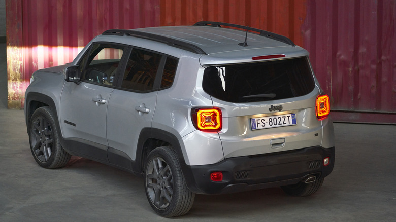 Rear view of a silver Jeep Renegade parked in front of a shipping container