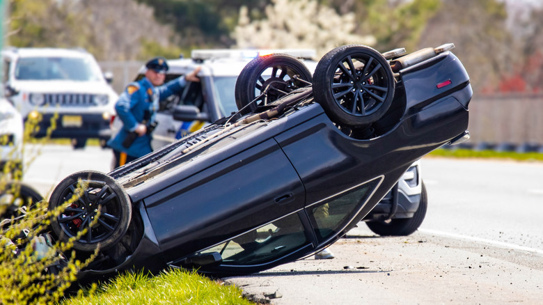 A vehicle rolled over on a New Jersey highway with a state trooper in the background.
