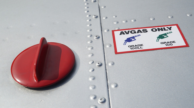 Close up of fuel tank filler cap on an aircraft, beside it is a sticker saying avgas only.