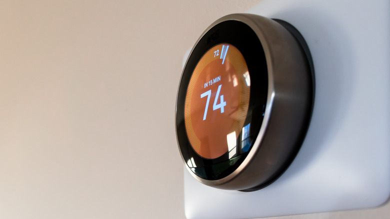 Smart thermostat on home wall displaying temperature