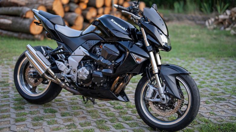 Kawasaki Z1000 parked on lattice driveway near a stack of wood