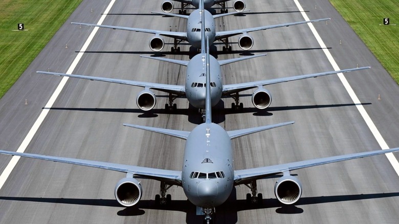 Multiple large gray colored U.S. Air Force aircraft lined up in a row on a runway.